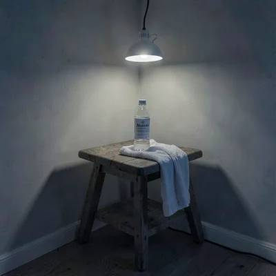 Nocturnal photo of a corner stool with a water bottle and towel under a single l