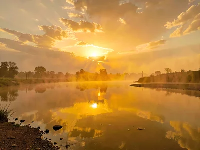 River surface reflecting amber sky through dust layer