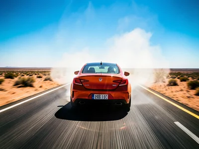 Car driving down desert highway stretching to horizon, summer heat haze