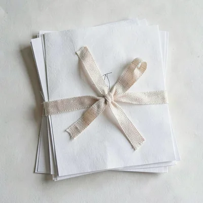 Top-down still life of a stack of design specimen pages tied with linen ribbon