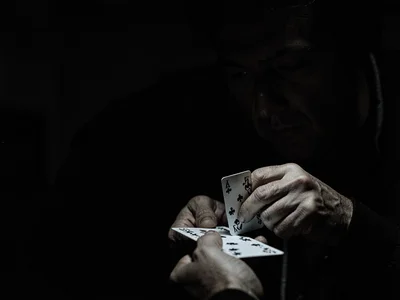 Hands dealing cards in darkness
