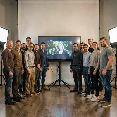 Wide ensemble studio crew portrait gathered around a screening monitor, painterl