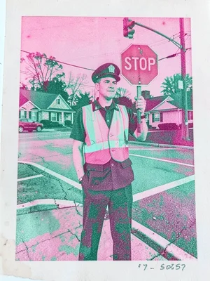 Crossing guard in a reflective vest holding a stop sign at a quiet suburban inte