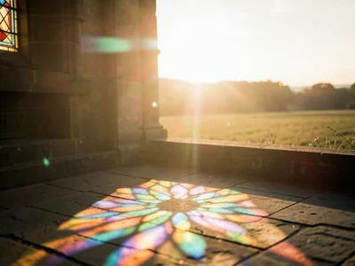 Light through stained glass creating rainbow pattern on stone floor