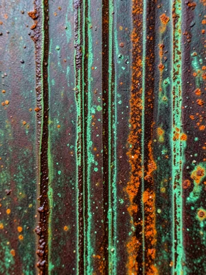 Architectural bronze rain streak patina, vertical green lines on dark brown from