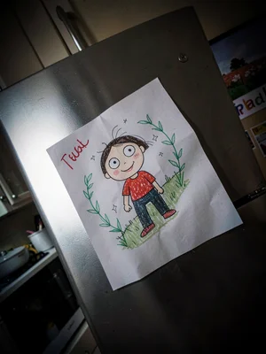Child's drawing hung proudly on fridge, the perspective making cheerful into omi