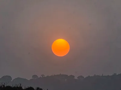 Sun as orange disk through haze