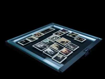 Old film negatives unspooled across the scanner bed, tiny frames visible with in