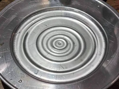 Water surface on metal plate showing circular standing wave pattern from 432Hz t