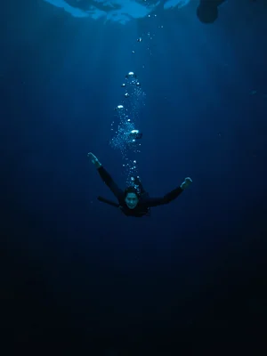 Diver suspended in deep blue, bubbles the only evidence of breath, the lonelines