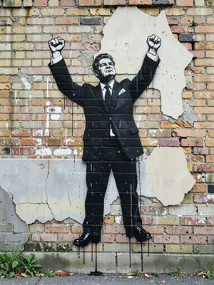 Classic fist-raised stencil figure on a crumbling brick wall, single-colour blac