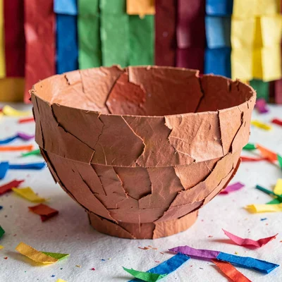 A finished papier-mâché bowl with a rough surface painted in a solid terracotta 
