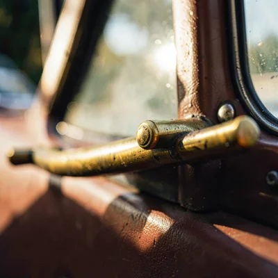 Close-up of brass handrail and rivet detail on a cab side, raking light