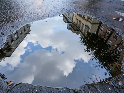 Puddle reflecting clouds, sky captured in ground-level water creating window int