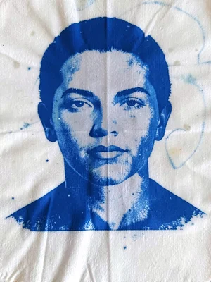 A face looking straight forward pressed onto sensitized fabric — bold Prussian b