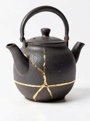 Old iron tetsubin teapot with gold-repaired crack running across spout base