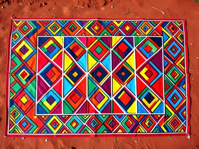 Ceremonial blanket with geometric border spread on red soil