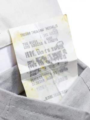 Crumpled receipt in pocket, fold lines creating white creases through faded text
