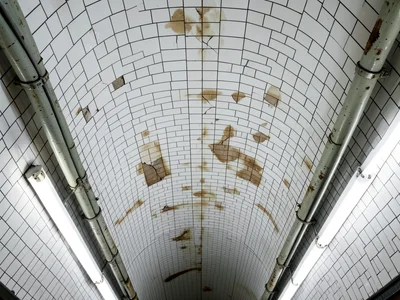 A New York subway station ceiling of white ceramic tile in a barrel vault, the t