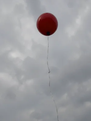 Child's balloon escaping into gray sky, the string still visible, the letting go