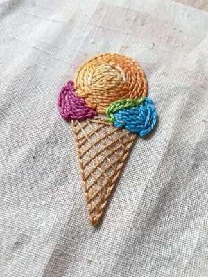 Hand-stitched ice cream cone on cotton, thread texture, colorful scoops