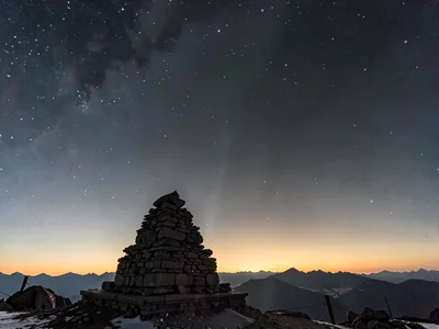 Summit cairn silhouetted against the thin air gradient toward space