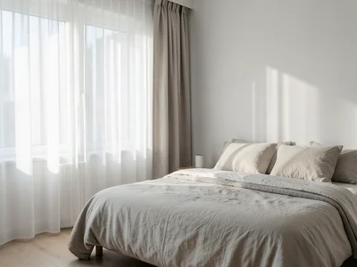 Morning light streaming through sheer curtains into a tidy bedroom with linen sh