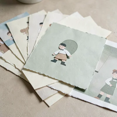 Papercraft hero of layered paper photo prints fanned out across a paper table, s