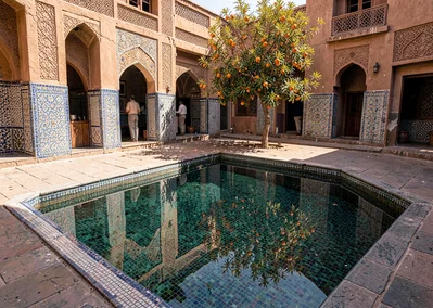 Geometric shadow play in Marrakech medina, mosaic pool with orange tree reflecti