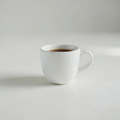 Minimalist photography of a single white coffee cup on a clean matte surface, centered composition, soft natural window 