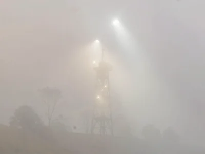 Twin range lights blinking in dense fog, only the closer tower drawn in detail,