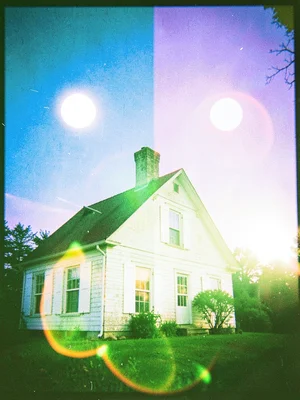 White painted shutters of an old farmhouse glowing under a sky split between blu