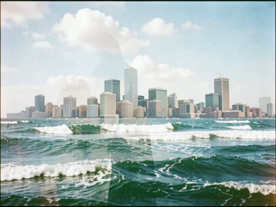 A city skyline overlaid with ocean waves, buildings appearing to rise from the s