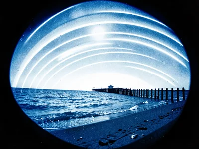 A beach groyne extending into sea, sun arcs above horizon over an equinox exposu