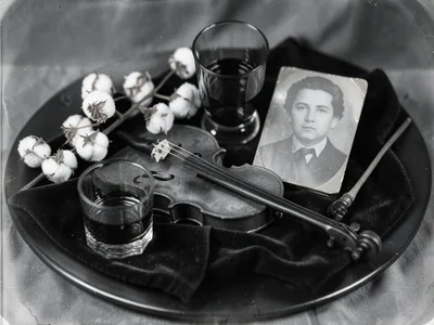 A fiddle laid flat on dark velvet cloth beside a bow, a half-empty whiskey glass