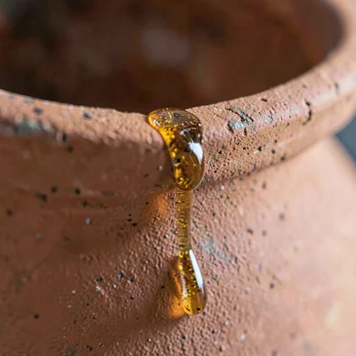 Macro of a terracotta amphora rim with amber wine residue trickling down the sid