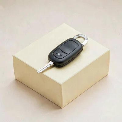 Catalog shot of a single car key fob on a butter-yellow block, soft wraparound l