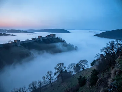 Fortress walls on hill above perfect fog sea