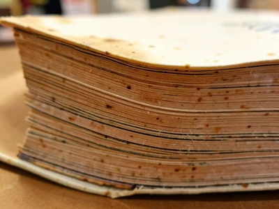 Book edge after heavy use, pages swollen unevenly from handling, some leaves pro