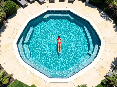 Symmetrical swimming pool from above, turquoise water, one red swimsuit figure
