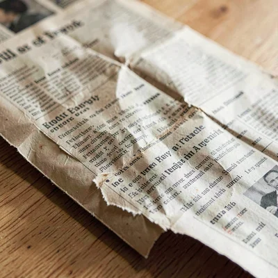 Paper-fold detail of a torn-and-restored newspaper, creases visible