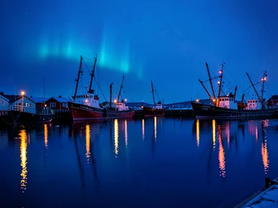 Polar night blue hour in Tromso, Norway, a row of fishing boats with their navig