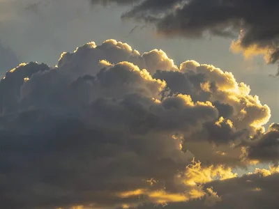 Evening light catching only the highest cloud edges in gold