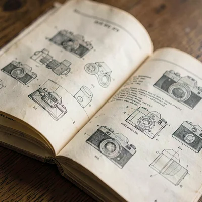 Paper close-up of an old camera manual fanned open at a diagram page