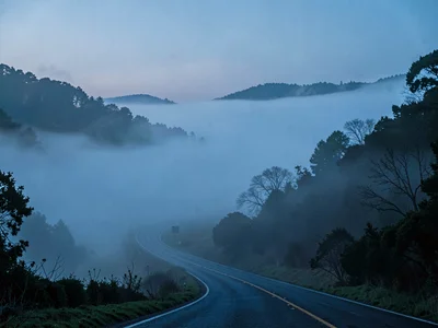 Road curving down into fog with only suggestion of continuation