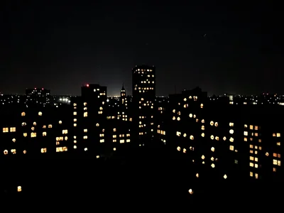 Cityscape at night but all lights are holes poked in black paper, light behind