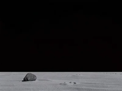 One small stone at corner of infinite grey sand beach