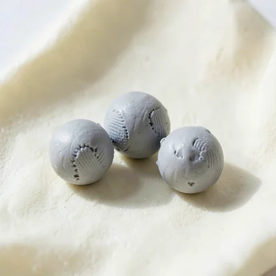 Three putty-grey marbles arranged in a loose triangle, fingertip dents along the