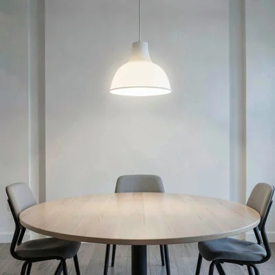 Soft white pendant lamp glowing above an empty round meeting table, calm hush