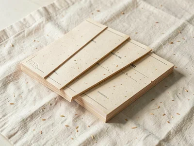 Stack of folded oat-card placeholder menus arranged in a slow diagonal across pa